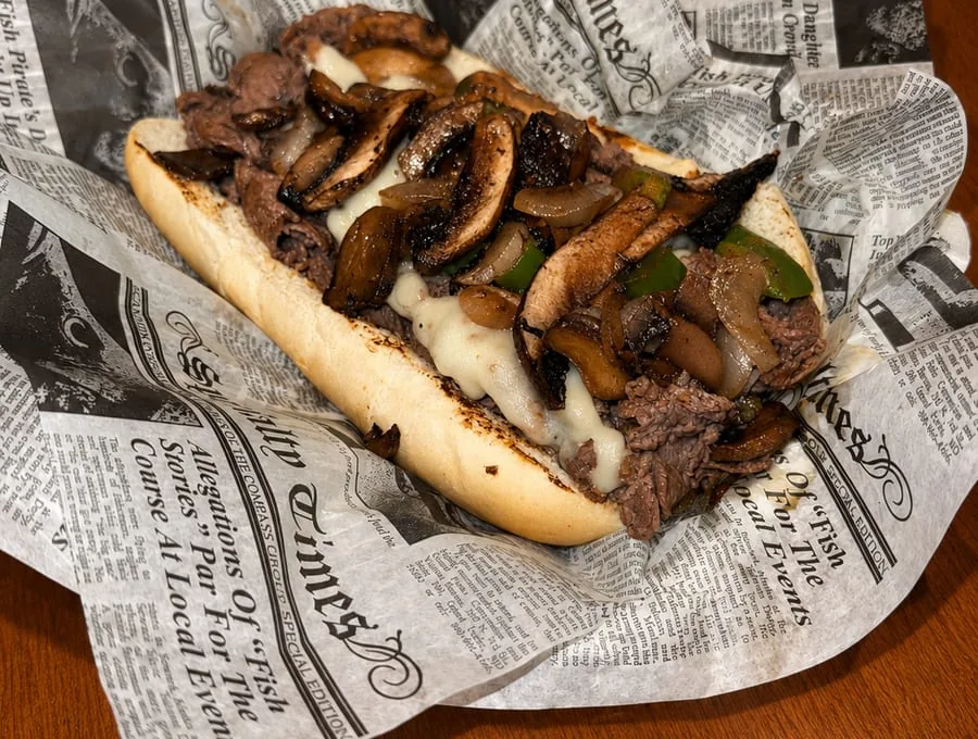 A loaded premium ribeye steak Philly wrapped in newsprint